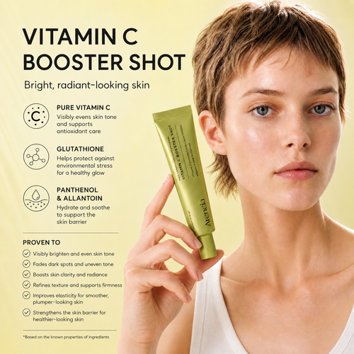 A woman with short light brown hair holds a green tube of Vitamin C Booster Shot against a pale yellow background with product claims and text.
